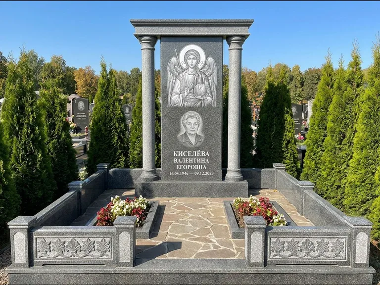 Памятник с гравировкой иконы: массивная стела с двускатным навершием-домиком — гравировка Николая Чудотворца, живая изгородь из туи, работа «Журавлёв» в Ростове-на-Дону