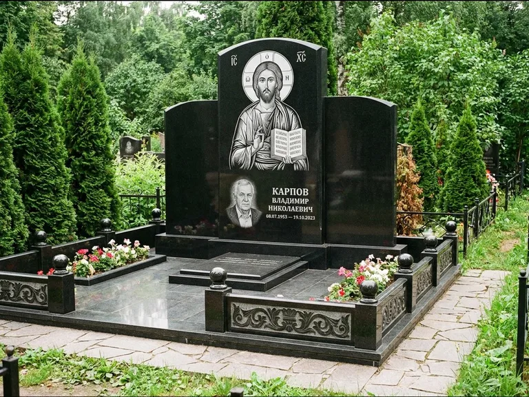Памятник с гравировкой иконы: широкая панорамная стела с золочёным нимбом — гравировка образа Матроны Московской, цветник с белыми хризантемами, работа «Мельникова» в Ростове-на-Дону