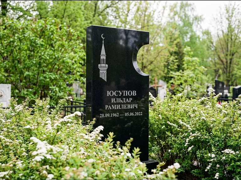 Мусульманский памятник с гравировкой мечети: стела с боковым вырезом в форме полумесяца — гравировка минарета с полумесяцем, низкие кусты спиреи в цвету, работа «Юсупов» в Ростове-на-Дону