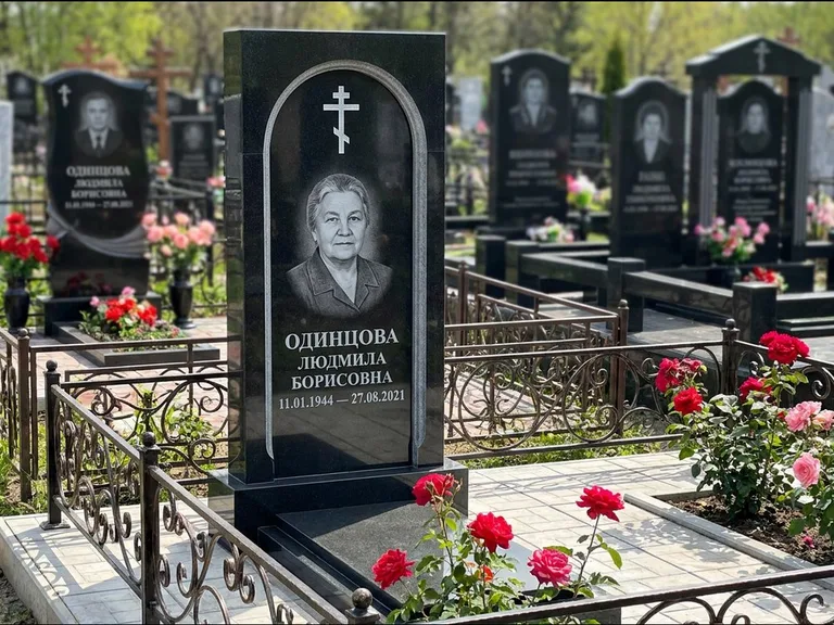 Памятник из чёрного гранита — скромная невысокая стела с крестом с терновым венцом, работа «Лаврентьева» в Ростове-на-Дону