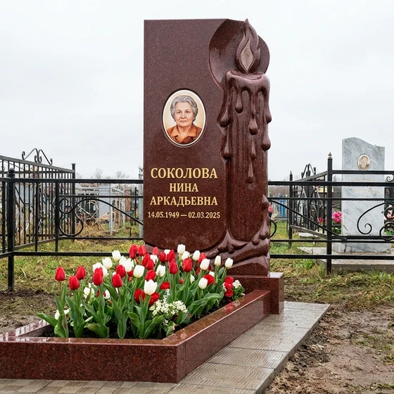 Мемориал с зажженной свечой из красного гранита
